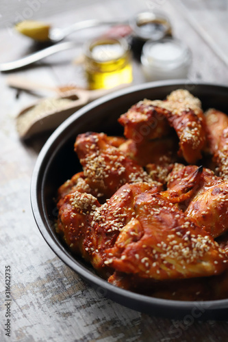 Selective focus. Appetizing buffalo wings in a pan. Baked chicken wings with sesame seeds.