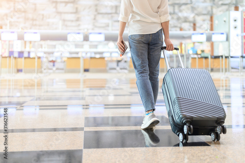 Canvas Print A woman with hand luggage walking in airport terminal