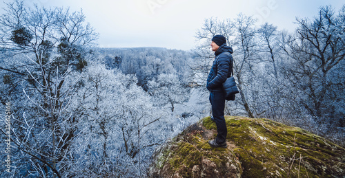 A man travels in mountains. Winter hike in the forest. Tourist on a walk in the winter season.