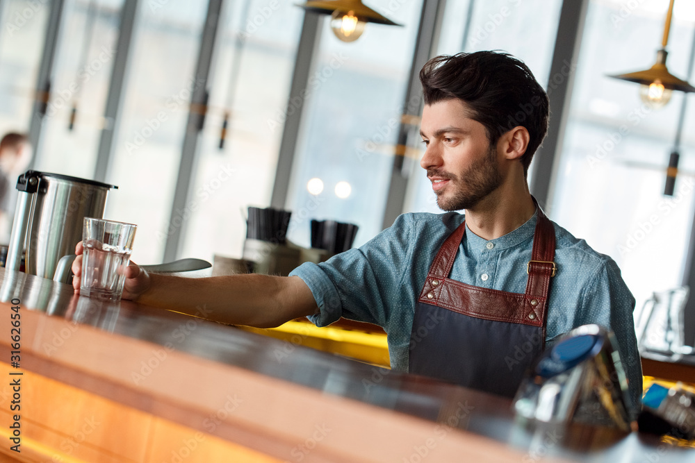 Fototapeta premium Professional Occupation. Bartender standing at counter serving glass smiling joyful