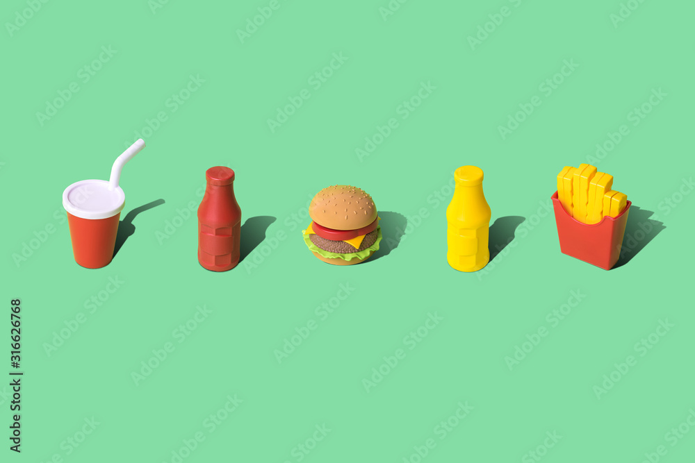 Junk food composition made of disposable cup, mustard and ketchup bottles with burger and french fries abstract on green.