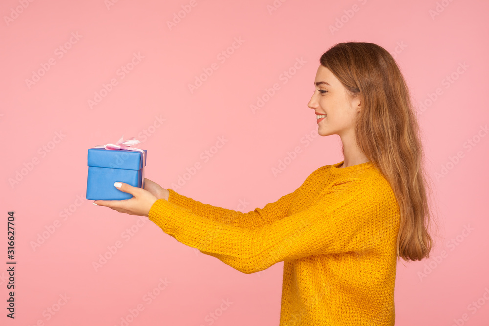 Take it! Portrait of charming generous red hair woman in sweater giving small gift box to the side and smiling, offering holiday present, charity. indoor studio shot isolated on pink background Take it! Portrait of charming generous red hair woman in sweater giving small gift box to the side and smiling, offering holiday present, charity. indoor studio shot isolated on pink background