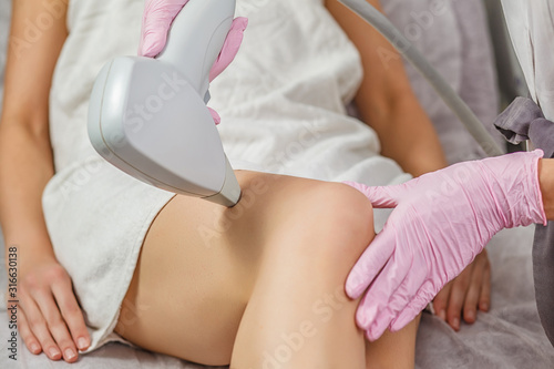 Epilation Treatment In Cosmetic Beauty Clinic. Partial view of young woman receiving laser hair removal epilation on thigh. laser skin care concept.