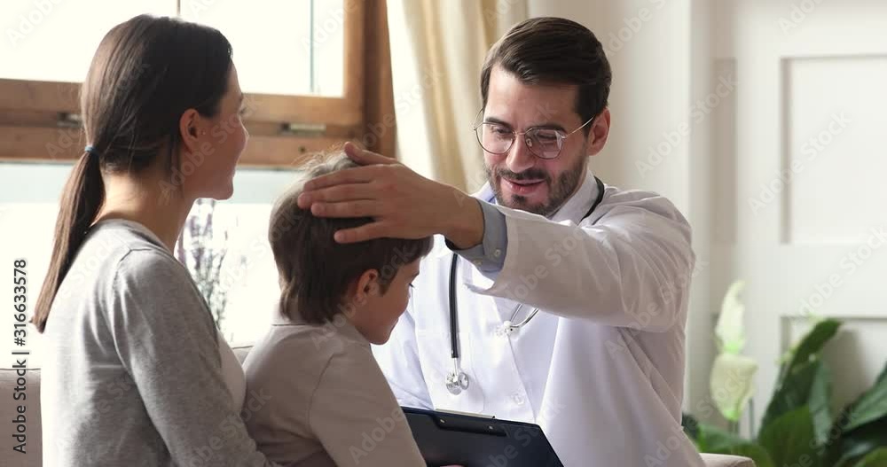 Happy caring male doctor encouraging kid boy patient at checkup