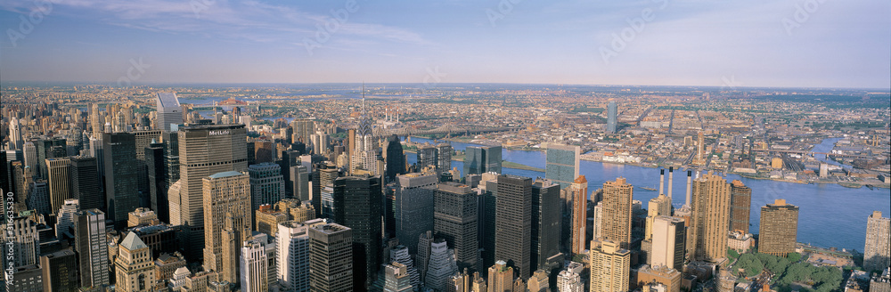 This is an aerial view of Manhattan with a view of the Empire State Building, the East River and Queens, the City Corp Building, the Met Life Building, and the U.N. Building.