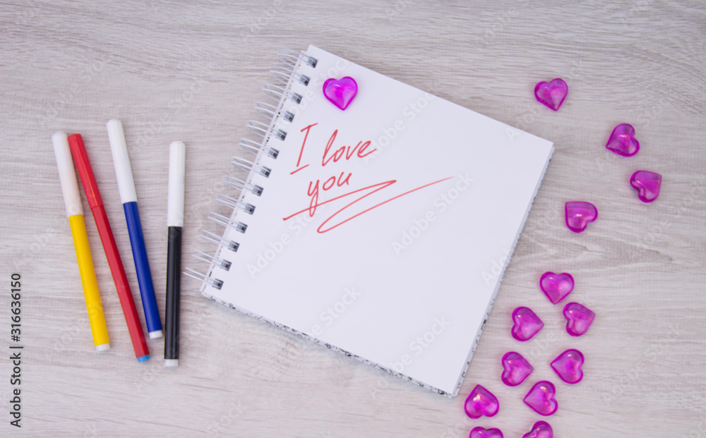 I love a pink letter, a Valentine card, a Notepad with the words I love you and a pen lying on a white background. Valentine day. Love letter. Marker writing I love a pink letter, a Valentine card, a Notepad with the words I love you and a pen lying on a white background. Valentine day. Love letter. Marker writing