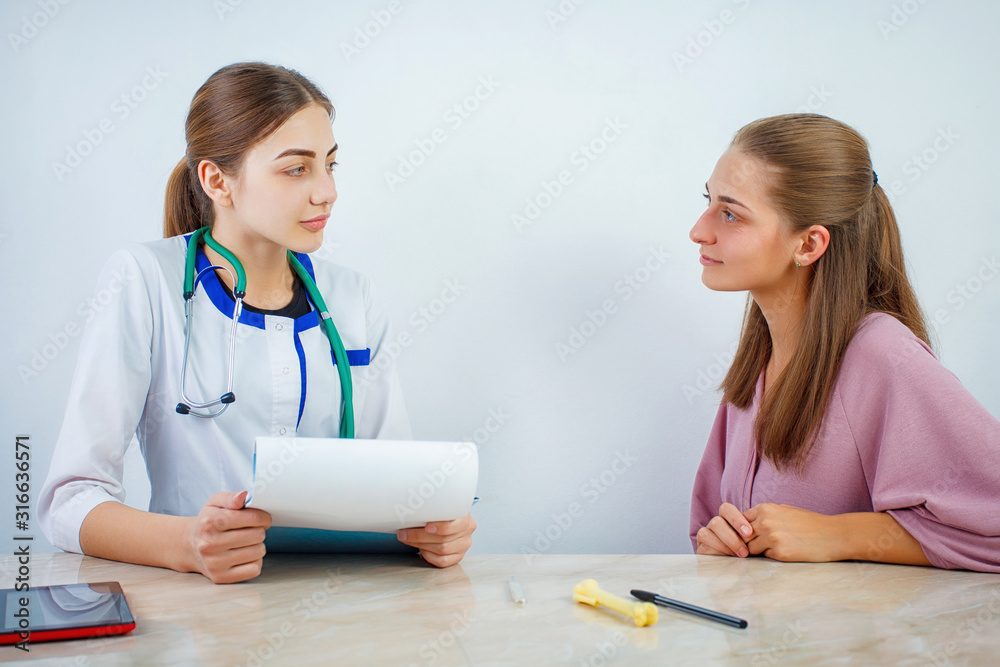 Doctor and patient talking while sitting at the desk in hospital office. Medicine and health care concept Doctor and patient talking while sitting at the desk in hospital office. Medicine and health care concept