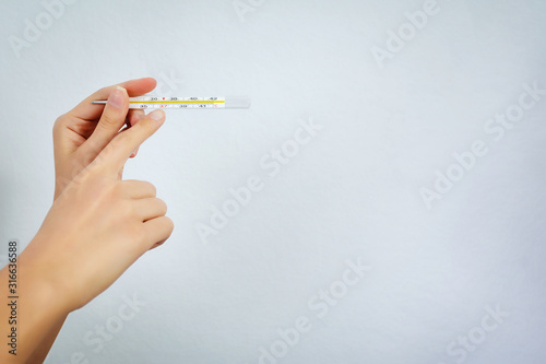 Thermometer for measuring body temperature in hand isolated on white background. Close-up. Copy space. Medicine and health care concept