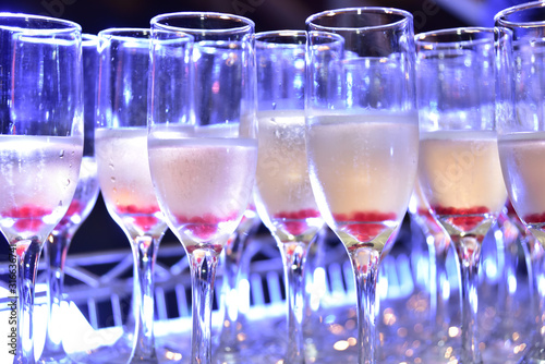 sparkling champagne drinks in crystal glass with blue light for blurred texture background with noise