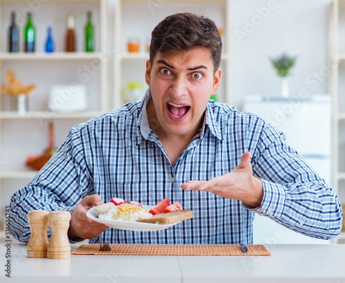 Young husband eating tasteless food at home for lunch