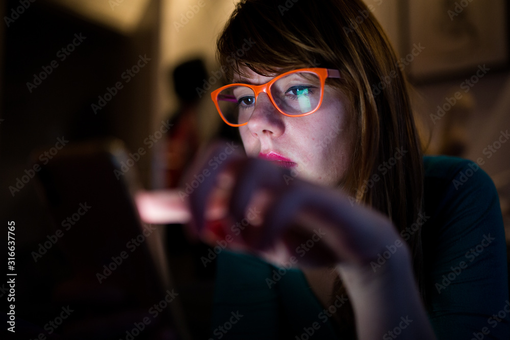 Hipster girl with glasses looking at her mobile phone Hipster girl with glasses looking at her mobile phone