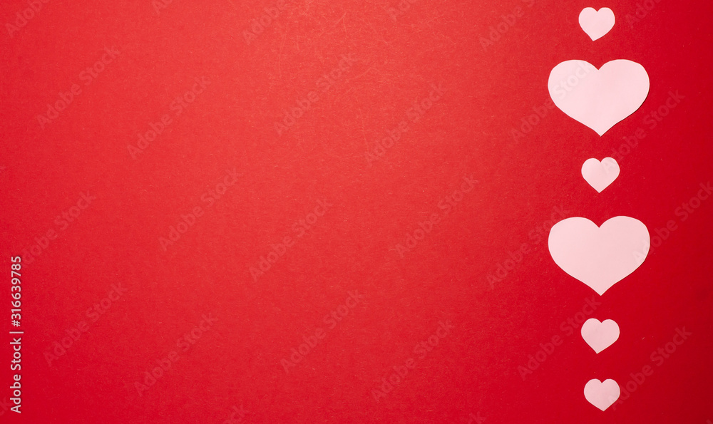 Pink hearts on red background on the right side. Valentines day concept. Flat lay top view with copy space.