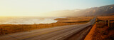 This is Route 1also known as the Pacific Coast Highway. The road is situated next to the ocean with the mountains in the distance. The road goes off into infinity into the sunset.