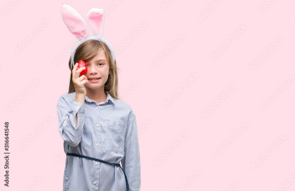 Young blonde child wearing easter bunny ears with a happy face standing and smiling with a confident smile showing teeth Young blonde child wearing easter bunny ears with a happy face standing and smiling with a confident smile showing teeth