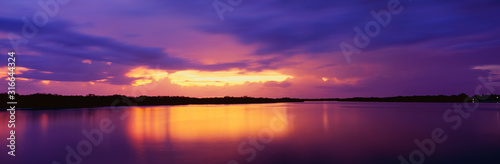 This is the ocean and Pine Island at sunset. There is a pinkish purple cast in the sky that is reflected in the water. The nearby land is in silhouette. © spiritofamerica