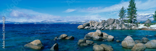 This is Lake Tahoe after a winter snow storm. There is a full moon over the lake and snow on the sandy shore.