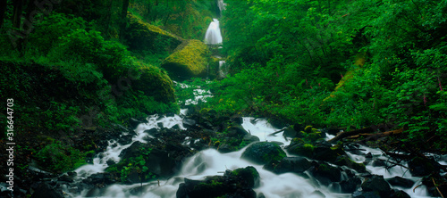 This is the Wahkeena Falls at the Columbia River Gorge. The falls are flowing over the rocks beneath it. photo