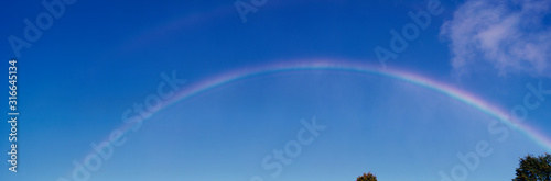 This is a rainbow against a blue sky with a few white clouds. It was taken near Niagara Falls.