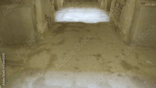 Camera tilt up from floor to reveal long corridor toward the entrance door inside the underground Tomb of Nefas Mawcha at the Northern Stelae Field in Aksum, Ethiopia photo