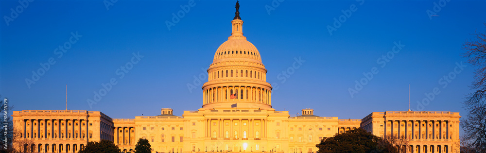 This is the U.S. Capitol at sunset. It is set against a blue sky.