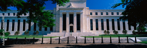 This is the Federal Reserve Bank, also known as The Fed where they make monetary policy. Its Federal Chairman is Alan Greenspan. It is an all white building with a green tree on either side of it. photo