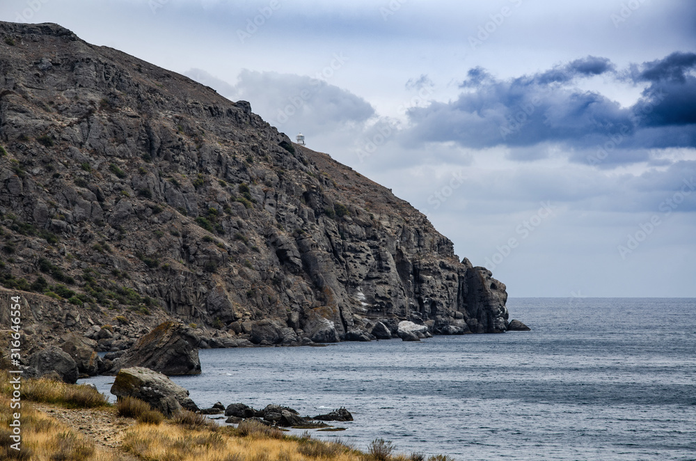 Mountain seascape. Large textured rock on the sea coast. Travel and adventure.