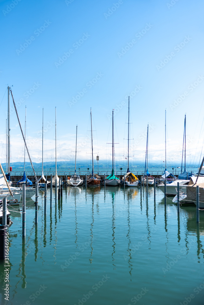 Picture of row of luxury sailboats reflected in water, yacht port on the bay summer vacation active lifestyle holiday concept text space