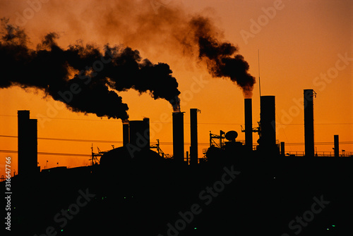 This is a Ford factory at sunset. These are smokestacks contributing to the pollution in the air.