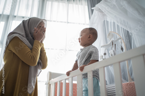 asian muslim mother play peek a boo with her son at home photo