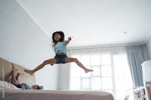 jumping young kid on the bed at home