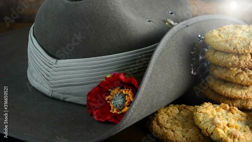 Australian Anzac biscuits with soldier slouch hat on dark vintage background with remembrance red poppy for Anzac Day or Remembrance Armistice Day. Slow panning with lens flare.