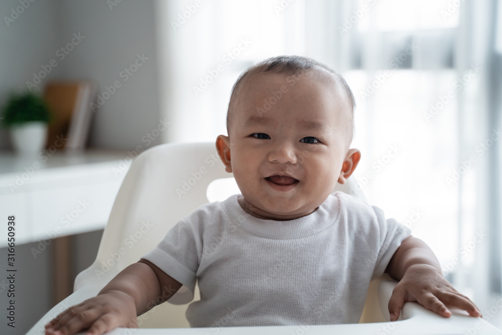 happy asian baby boy sitting on high chair smiling happy asian baby boy sitting on high chair smiling