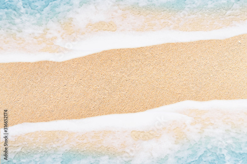 Top view soft wave and white foam of ocean on sand beach.