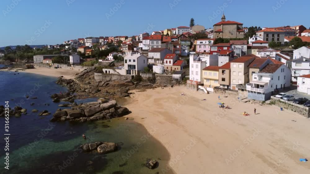 Aerial pedestal down shot of a beautiful beach in Palmeira, Spain with visible clear sand and beach houses. Beautiful village of Galicia Aerial pedestal down shot of a beautiful beach in Palmeira, Spain with visible clear sand and beach houses. Beautiful village of Galicia