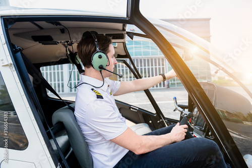 A Airline pilot wearing uniform sitting inside with epaulettes and headset to connect with another pilot on board passenger. photo