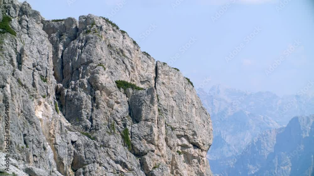 Rocky cliff mountain with almost vertical slopes, panning panorama with rocky mountain chain in the background. Telephoto lens, high quality 4k prores Rocky cliff mountain with almost vertical slopes, panning panorama with rocky mountain chain in the background. Telephoto lens, high quality 4k prores