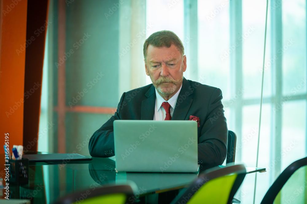 A businessman wearing suit thinking work with laptop computer and document on desk for successful business at office work place. A businessman wearing suit thinking work with laptop computer and document on desk for successful business at office work place.