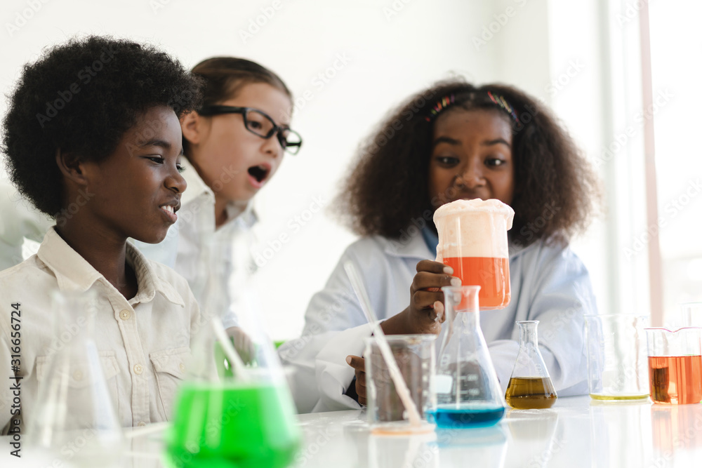 Group of teenage students learning and doing a chemical experiment and holding test tube in hands in the experiment laboratory  class on table at school.Education concept - obrazy, fototapety, plakaty 