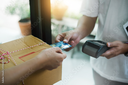 Young woman being paid with pos and credit card to parcel delivery.
