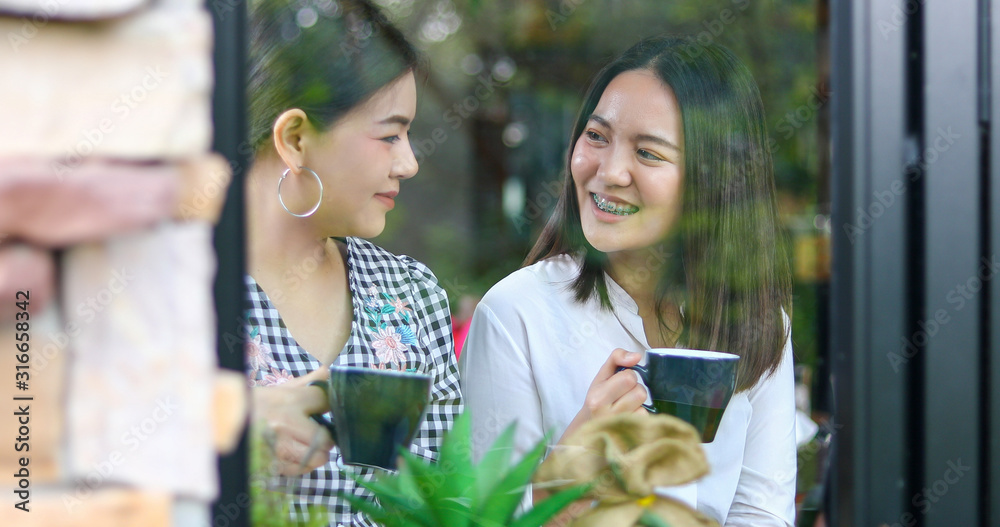 Fototapeta premium Two asian women drinking coffee and Cheerful women gossiping in a cafe
