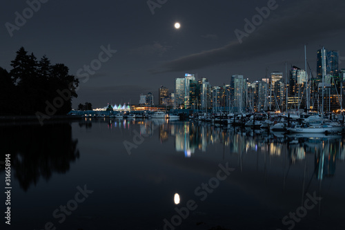 Downtown vancouver canada on a clear night with a full moon reflection