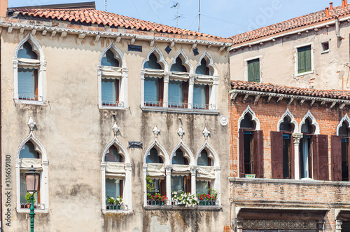 Facade of venetian houses with typical old venetian windows on it. Sunny day. Venice, Italy photo