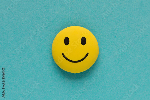 Yellow funny smiley face on blue background. Positive mood concept.