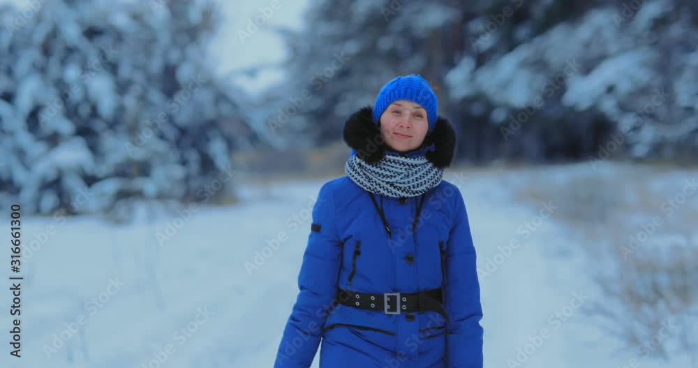 Beautiful woman walks in the winter on a snowy road and smiles. Winter forest landscape, happy woman walks. Portrait view. Beautiful woman walks in the winter on a snowy road and smiles. Winter forest landscape, happy woman walks. Portrait view.