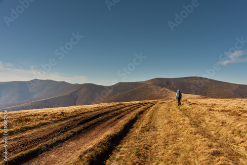 Adorable autumn landscapes in Carpathian mountains with beautiful tourist girl traveling with red tent