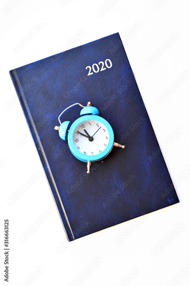 Daily planner calendar for 2020 year and blue retro classic alarm clock showing midnight or noon isolated on white background. Vertical frame