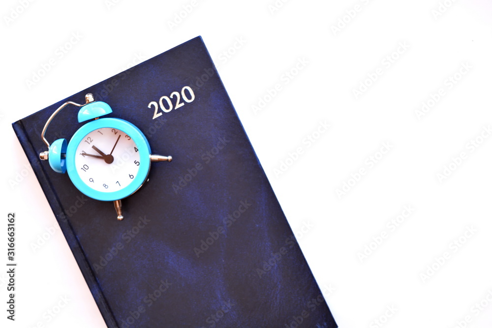 Daily planner calendar for 2020 year and blue retro classic alarm clock showing midnight or noon isolated on white background. Horizontal frame Daily planner calendar for 2020 year and blue retro classic alarm clock showing midnight or noon isolated on white background. Horizontal frame