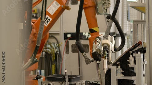 Close up automated industrial robotic arm / robotic center / automated workplace / robotic glueing headlamp groove in industrial modern automotive factory 4K