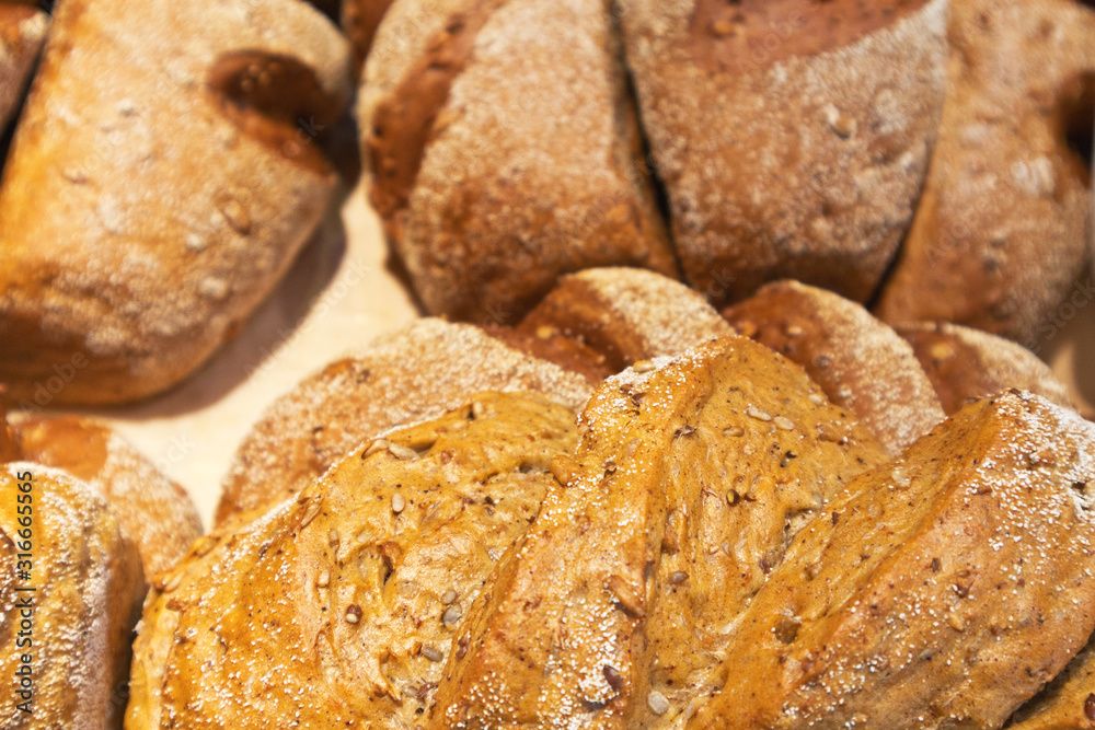 A close-up view on wholesome rye freshly baked bread with flax and sunflower seeds in a bakery. Healthy diet food. Edible background. Shallow depth of field