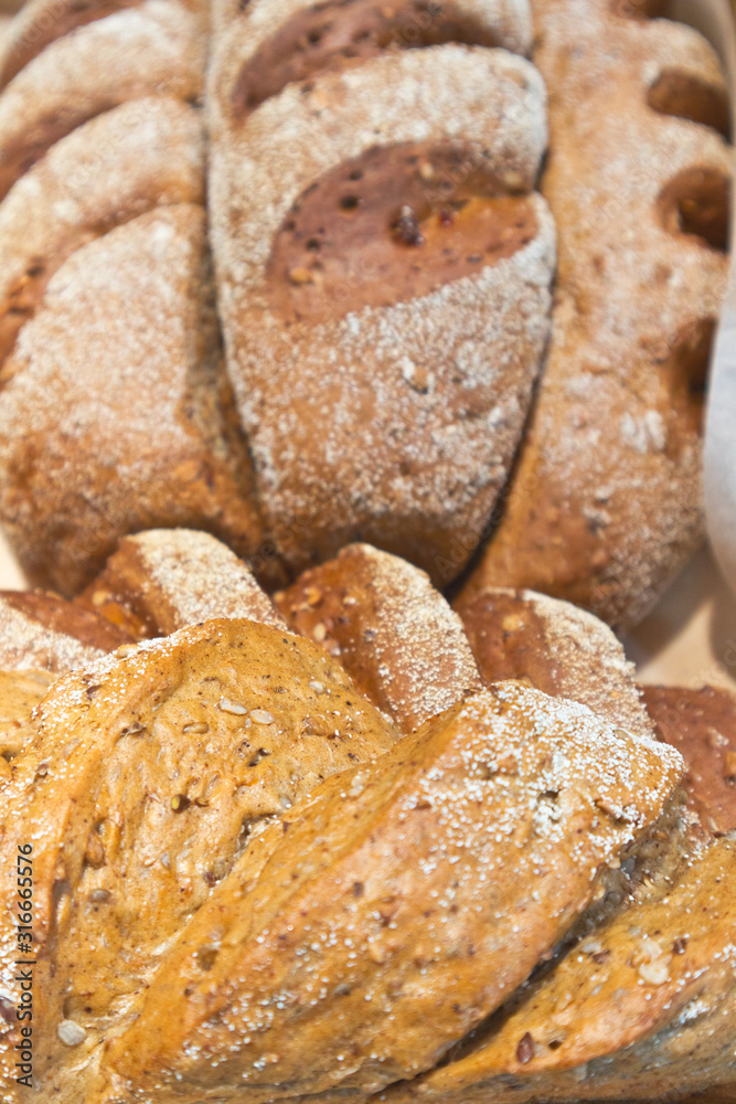 Long loaves from whole grain rye flour with flax and sunflower seeds in a bakery. Healthy diet food. Edible background, flat lay, close-up. Shallow depth of field
